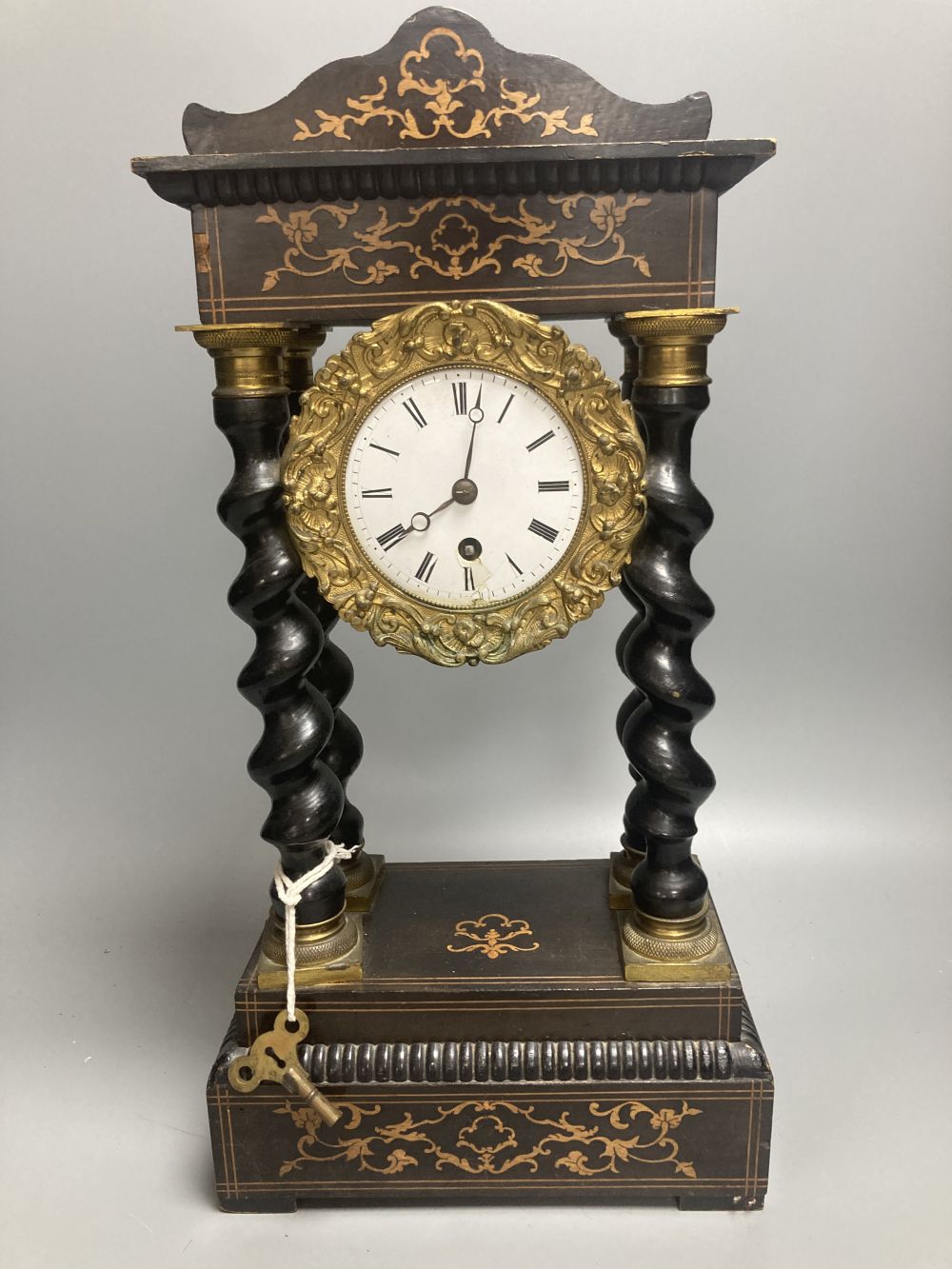 A 19th century French portico ebonised mantel clock, enamelled dial and timepiece movement, gridiron pendulum, 44cm high
